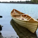 Cover image: A small boat like a canoe, parked on a beach at a small lake.